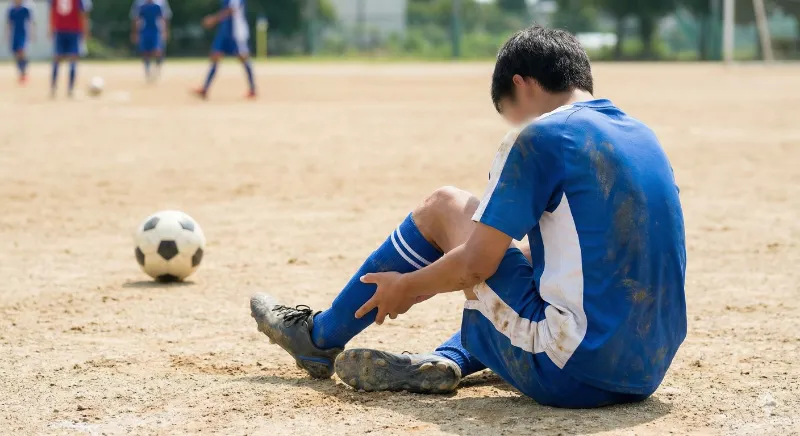 知多市で打撲を負ってしまい座り込むサッカー少年